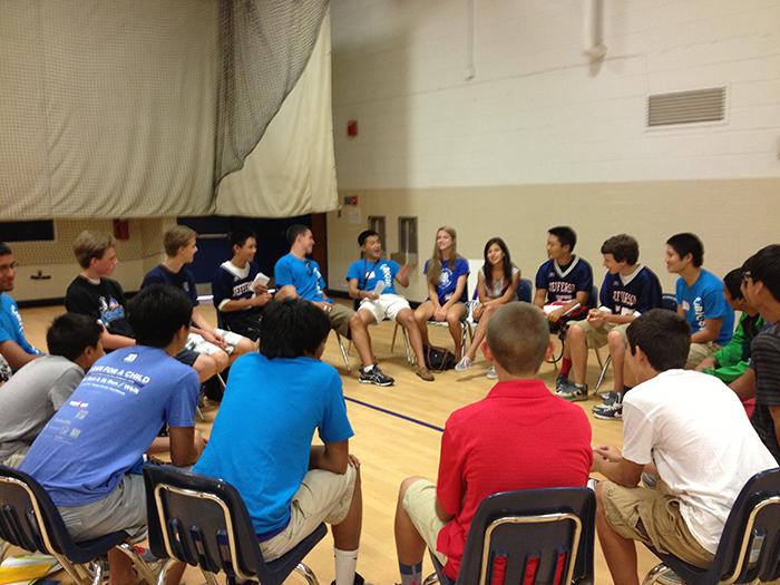 BigSibs and LittleSibs sit in a circle in Gym 2 as they play icebreaker games.