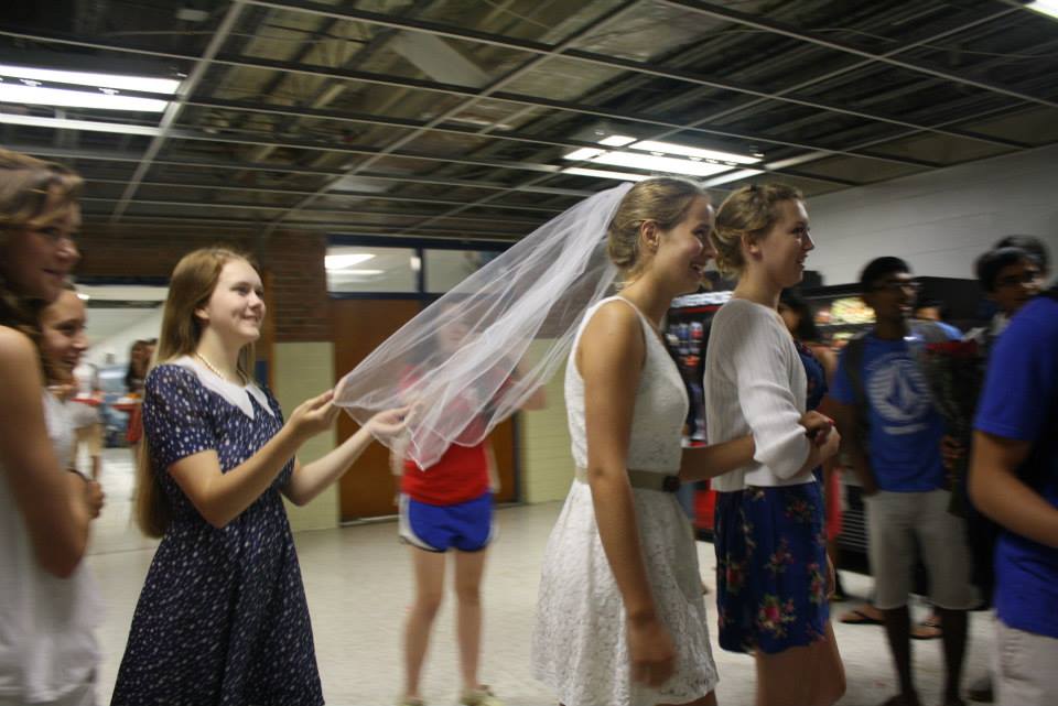 Junior Sophie Bennett is led by juniors Annie Thomas and Caroline Culberson down the aisle.