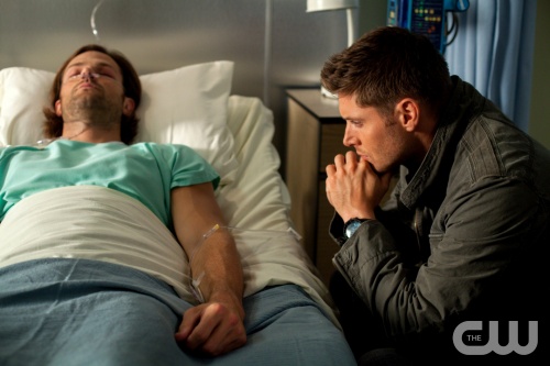 Sam Winchester in a hospital bed, with his older brother, Dean Winchester, sitting helplessly by his side.
Photo courtesy of The CW's official "Supernatural" website.