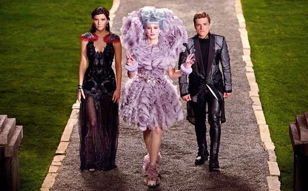 Effie Trinket (Elizabeth Banks) leads the way for Katniss Everdeen (Jennifer Lawrence) and Peeta Mellark (Josh Hutcherson) in Catching Fire. (Photo courtesy of thehungergamesexplorer.com.)