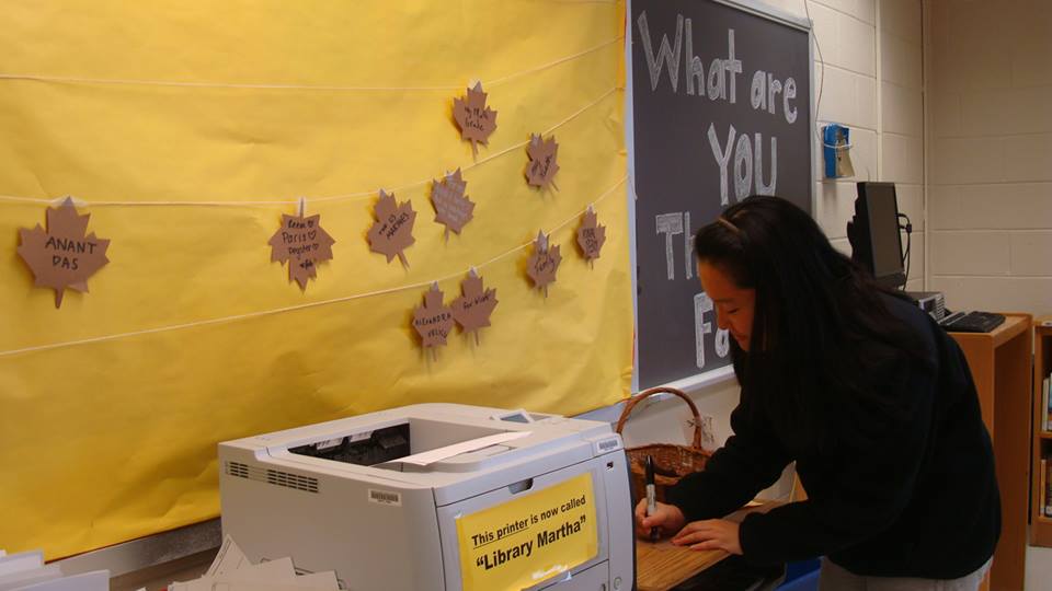 sophomore Augene Park writes on a paper leaf to put on the display in the library.