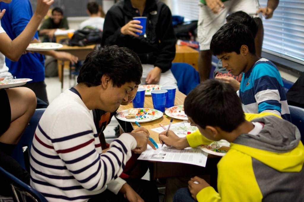 Sophomores Srikar Kosuri, Pranav Gulati and Haran Chithranjan contribute to the Write for Rights campaign while enjoying some holiday treats.