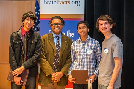 Winner Shomik Ghose (far left), Runner-up Akshay Balaji (center right), and 3rd place Winner Jacob Gerrish (far right) stand alongside DC Brain Bee Moderator Benjamin Walker (center left) in victory after the competition concludes.