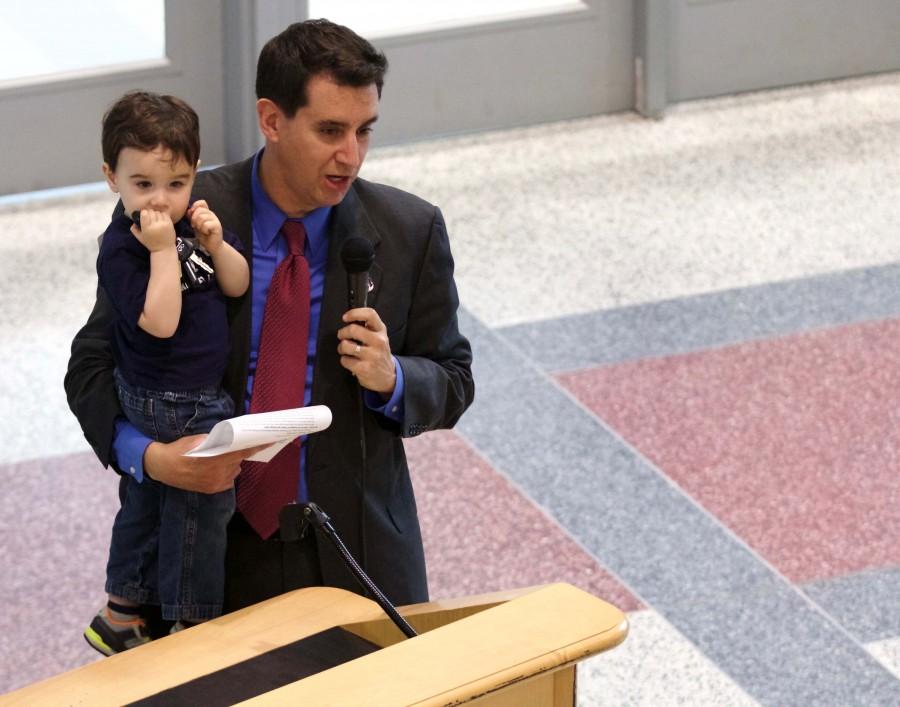 Holding his son Luke, Dr. Evan Glazer gives opening remarks at the dome opening ceremony on March 10. Glazer has served as principal of TJHSST for the last ten years.