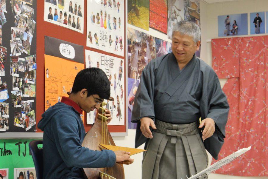 Student tries out the biwa as the satsuma-biwa master watches how well he is doing.