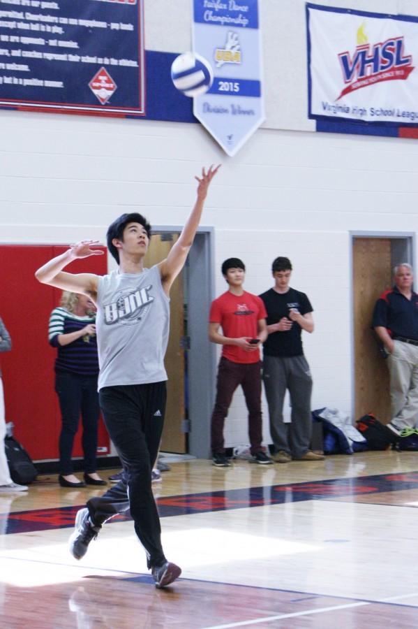 Senior Andrew Li sets a volleyball up to serve.