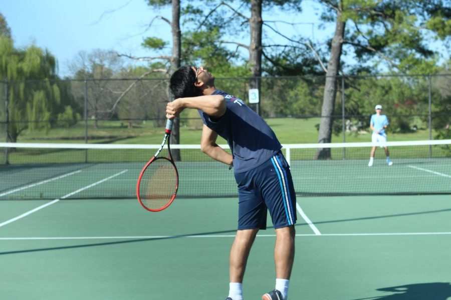 Reaching back, junior Neeraj Prasad serves the ball to his opponent in his singles match.