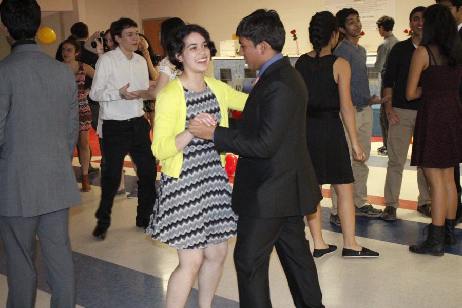 Sophomores Maya Parker and Paarth Jain dance together on the dance floor, surrounded by other dancing pairs.