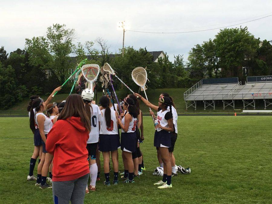 Junior Varsity lacrosse  players salute their final games victory through a ceremonial bashing of lacrosse sticks.