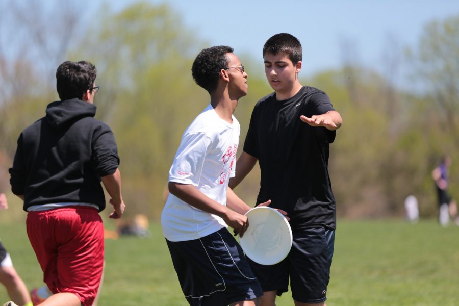 Junior Kirubel Akililu holds the frisbee in his hands, ready to pass to another teammate while trying to go through defense.