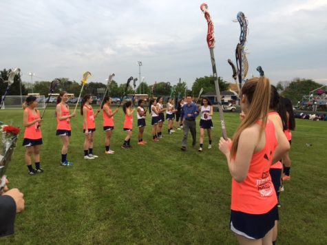 Senior lacrosse player Cece Xiao makes her way through the JV lacrosse teams path to accept a bouquet of flowers and handshake from Dr. Glazer.