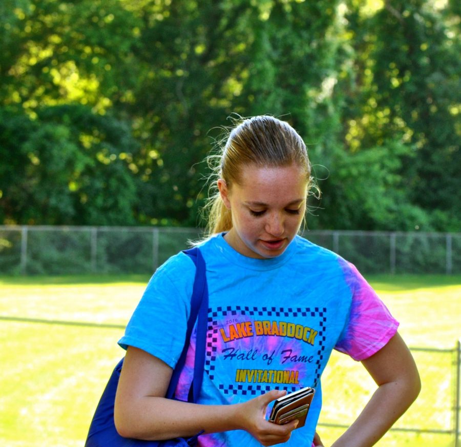 Rising senior Caroline Cox stares intently at her phone while playing Pokémon Go