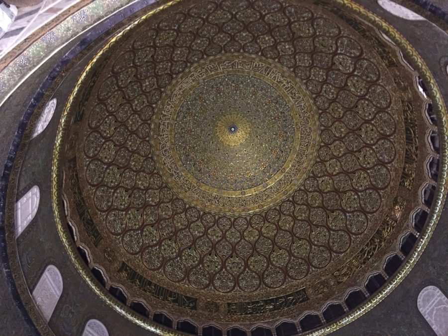 An inside view of the Dome of the Rock. The walls are covered with intricate geometric designs and Arabic calligraphy. 