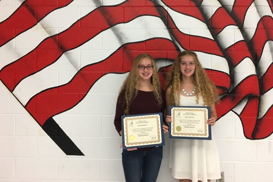 Madelyn and Miranda Khoury hold up their certificates honoring their For Love of Country essays.