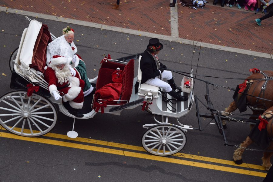 People dressed up as Santa Claus and Mrs. Claus at the Reston Parade with their sleigh and “reindeer” (horses).