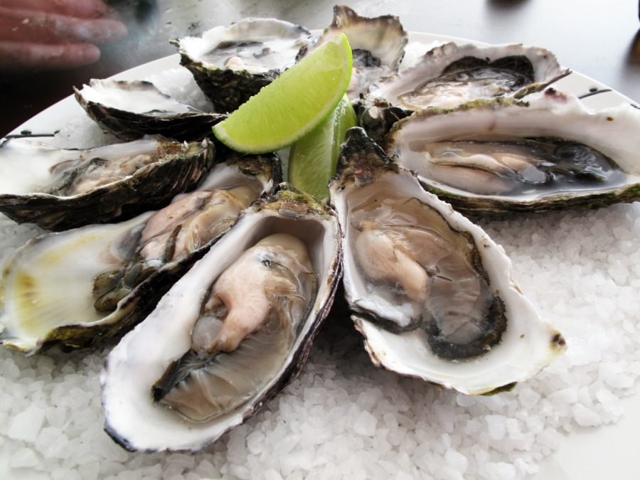 A platter of oysters topped with a lime for flavoring.