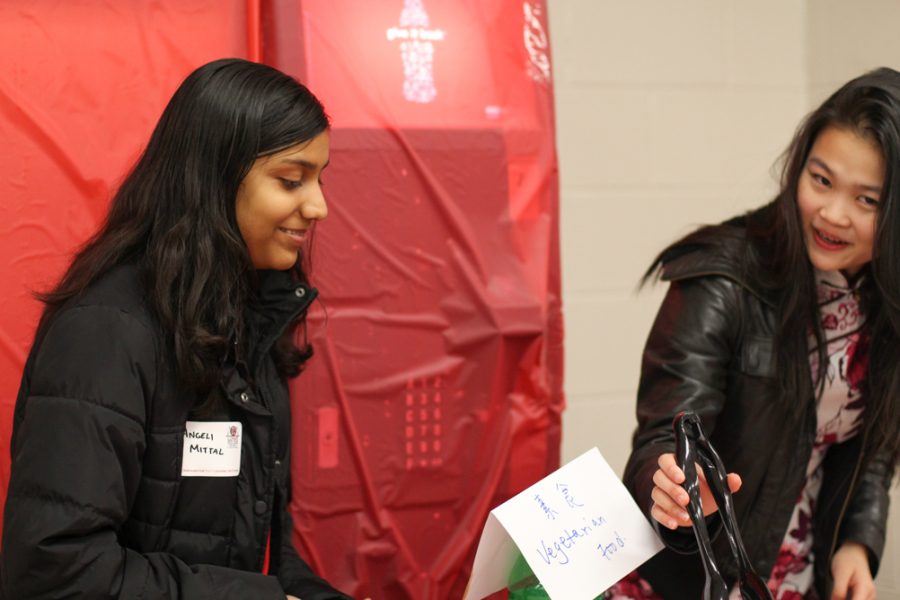 Freshmen Angeli Mittal and Isabelle Deng serve food. 