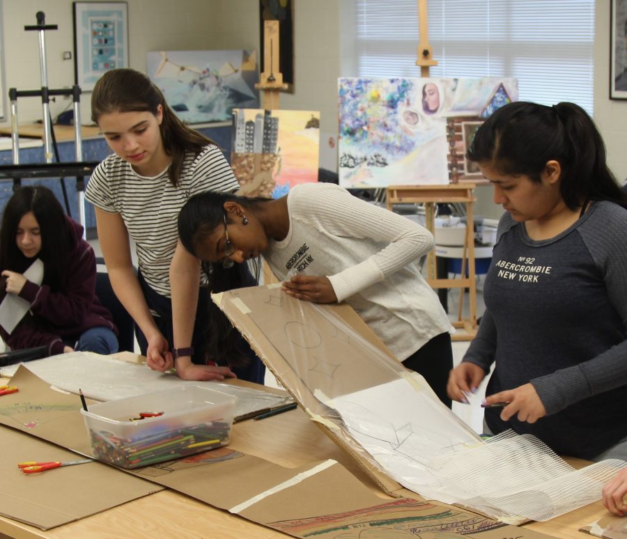 Art club members lay down preliminary sketches for mosaic to decide colors before creating the final product.