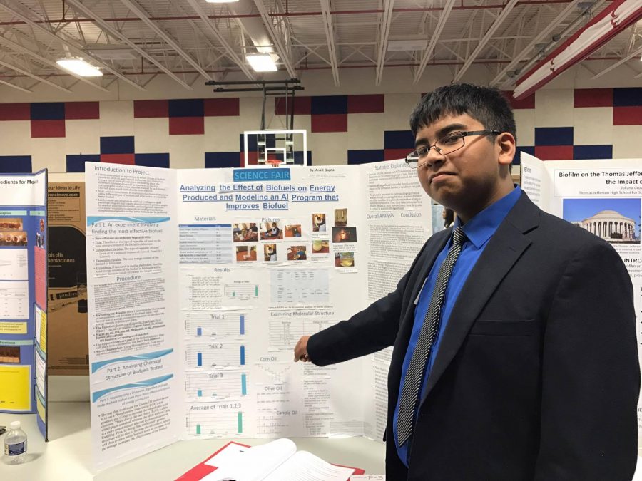 Ankit+Gupta+proudly+stands+next+to+his+science+fair+project+while+explaining+his+experiment+to+students+nearby.