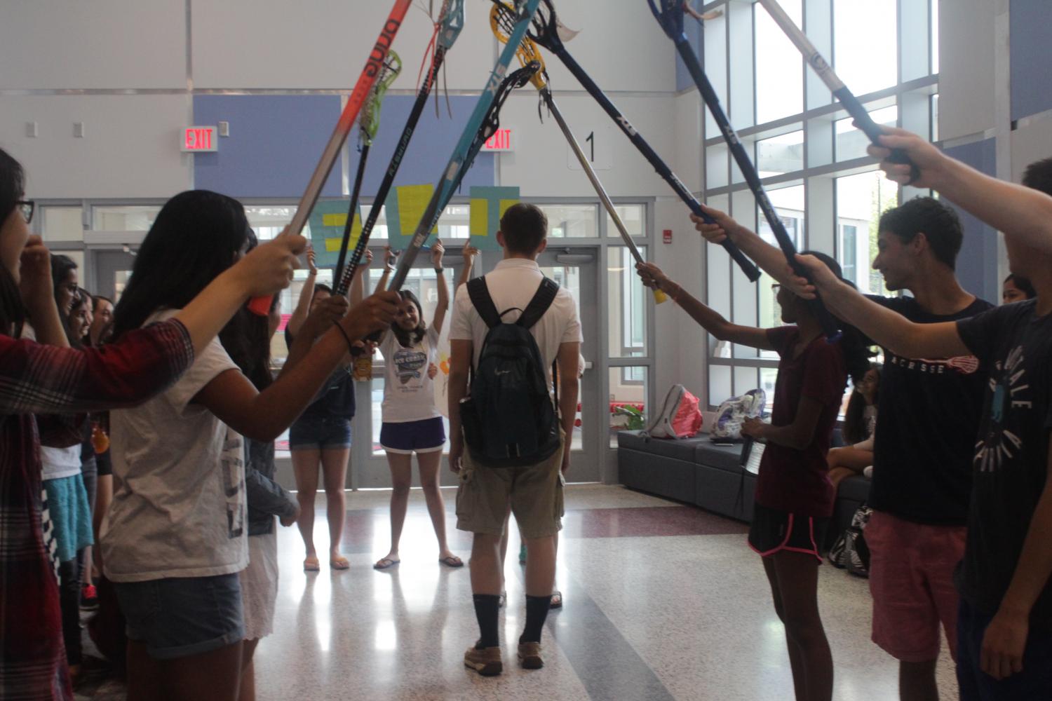 Lacrosse players hold up their sticks to make a pathway for Freshman Jessica Chen to ask Eli Kirtley to Sadies.