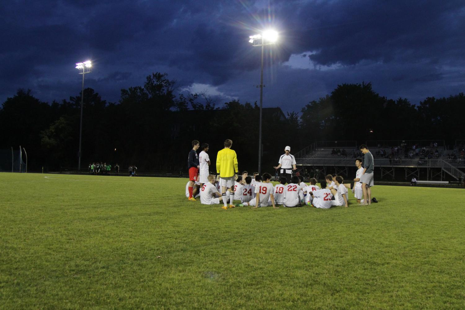 The boys soccer team get into circle with their head coach, Mr. Sean Burke, taking the lead in the discussion.
