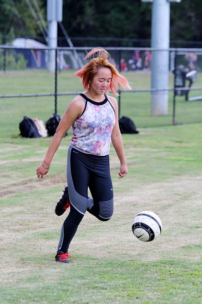 Junior Shay Le plays with a soccer ball in the baseball field.