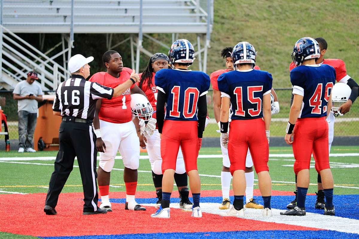 From left to right: Seniors Wonwook Do, Danny McCray, and Clayton Reppert stand in the center of the field for the coin toss at the start of the game.