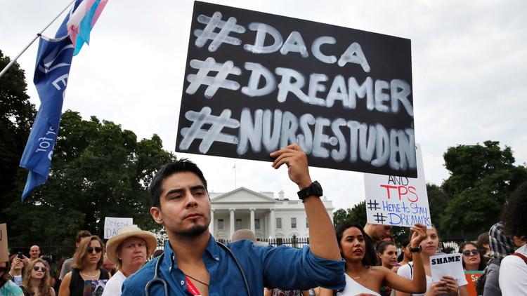 Photo courtesy of the Los Angeles Times. Carlos Esteban, a nursing student from Woodbridge, Va., protests with a group of people outside of the White House in support of DACA.