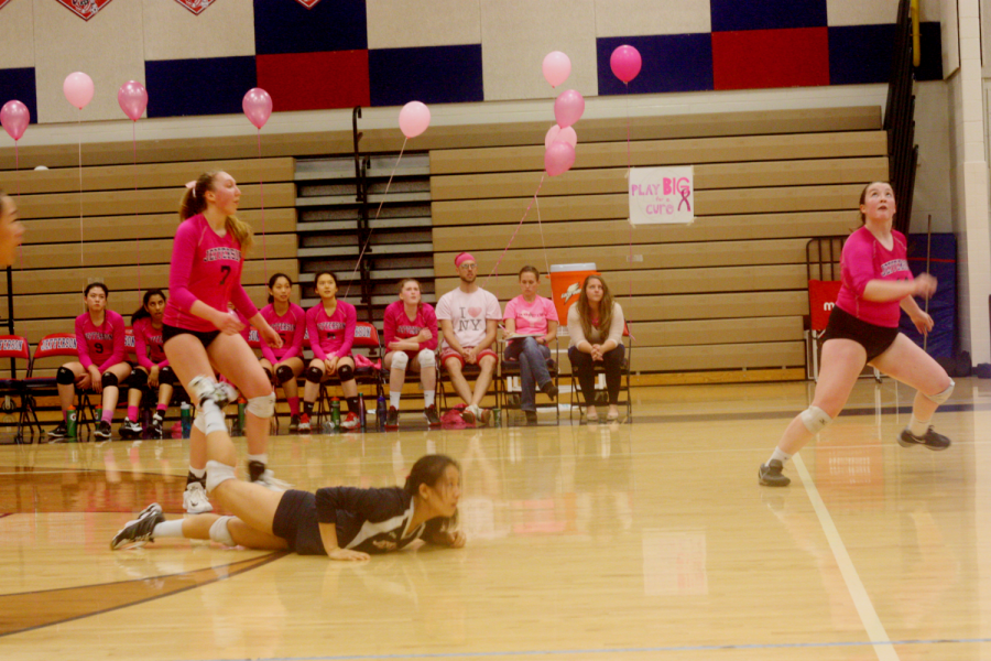 The team goes low to ground a ball in the opposing team's court.