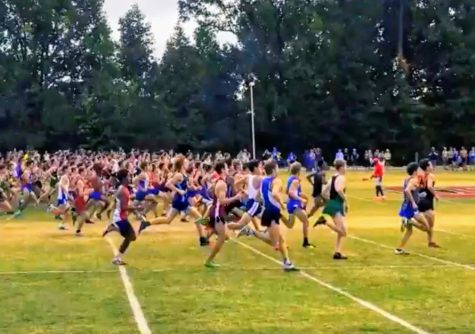 Runners competing in the varsity boys 5000 meter event, including 9 athletes from Jefferson, start the race as spectators cheer on.
