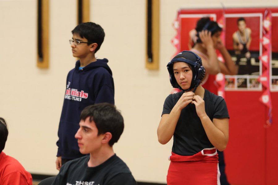 In+preparation+for+her+upcoming+match%2C+freshman+Brianna+Ta+puts+on+her+ear+guard.+Despite+being+only+one+of+two+girls+on+Jefferson%E2%80%99s+varsity+wrestling+team+and+much+smaller+than+many+of+her+opponents%2C+Ta+placed+third+in+National+Districts+and+qualified+for+regionals.+%E2%80%9CPeople+are+usually+amazed+%5Bwhen+they+find+out+I+do+wrestling+and+jiu-jitsu%5D.+My+friends%2C+actually%2C+call+me+%E2%80%98Tata+Buff%E2%80%99%2C+and+on+the+wrestling+team%2C+my+nickname+is+%E2%80%98Warrior+Princess%E2%80%99%2C%E2%80%9D+Ta+said.