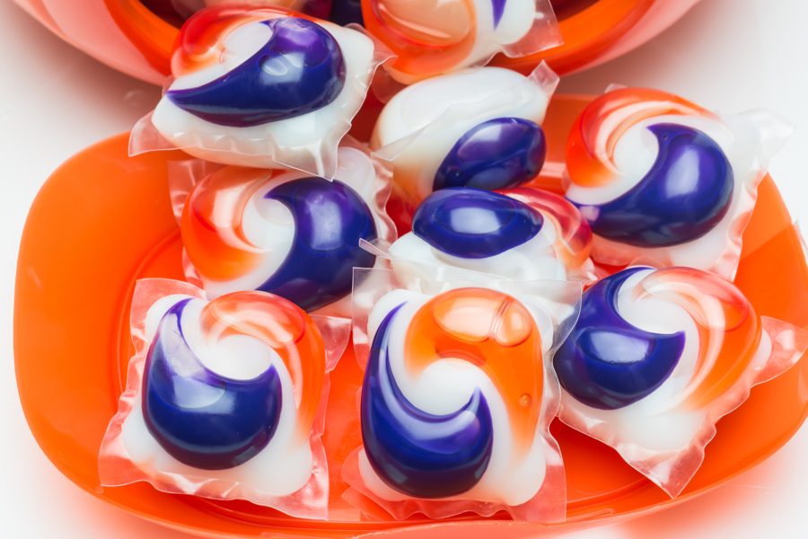 Close-up shot of tide pod capsules spilling out from their fishbowl-shaped container.