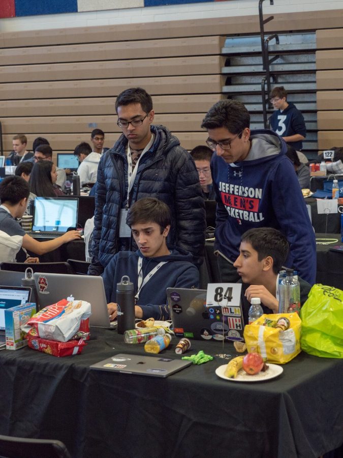 Working on their program, a team types on their computers while eating various snacks.