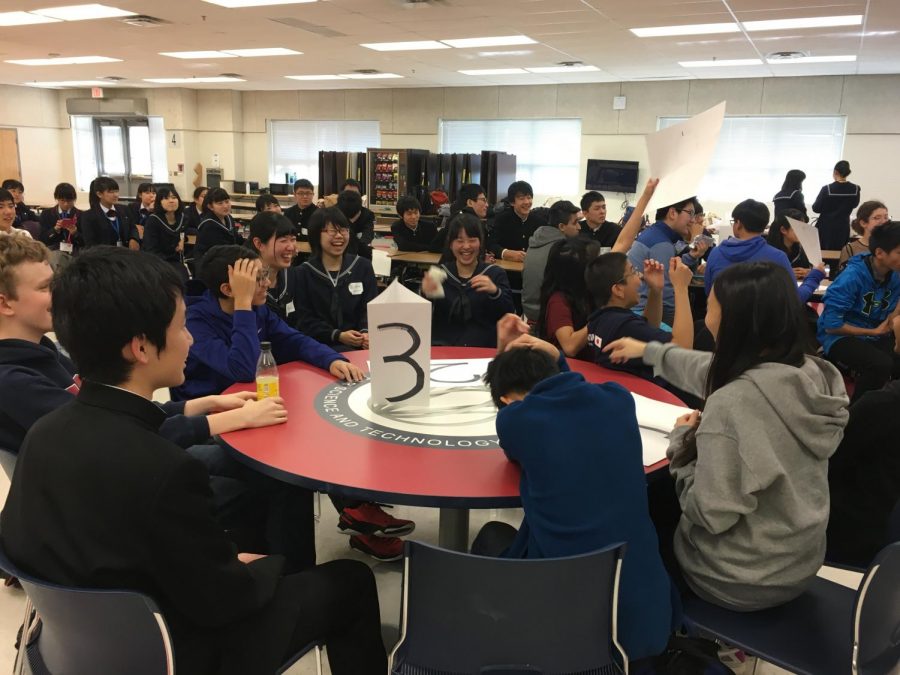 Visiting students from Fujishima High School laugh alongside Jefferson students as they rush to hold up their answer to a question. 