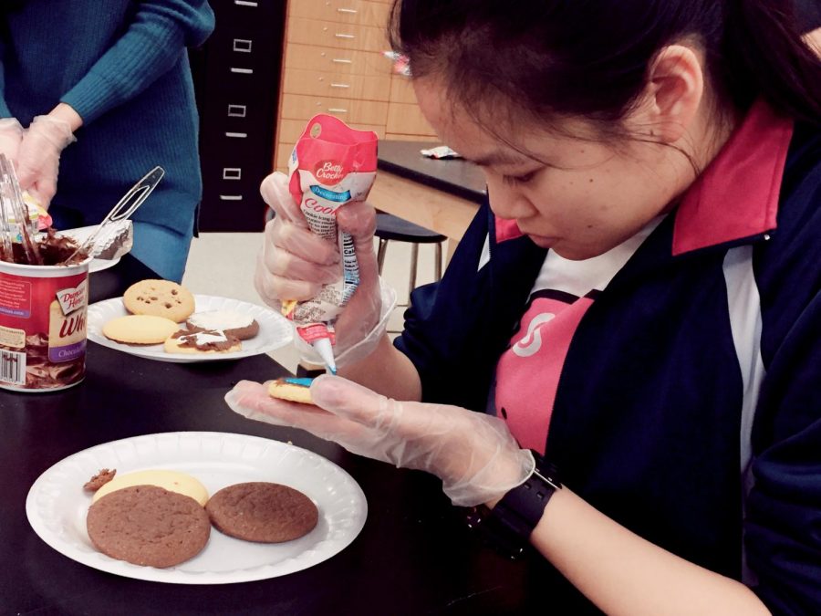 Junior Jennifer Liu decorates a plate of cookies with icing after finishing her thank-you card.