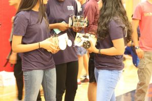 Holding their robots, freshmen converse with their friends before the competition.