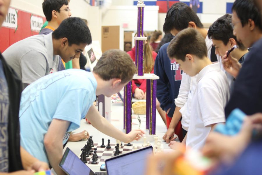 The TJ Chess Club discusses the game of chess as they prominently display a trophy.