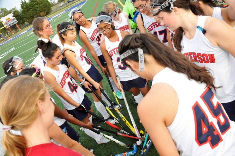 Listening+intently%2C+the+JV+field+hockey+team+huddles+around+the+coach%2C+Allie+Ivener%2C+before+a+game.%0A