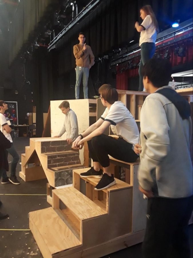 A group of actors and crew members listen to the director, Andrew Reid, give out instructions at the last practice before their first performance.