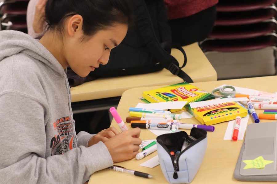 Senior Lilia Qian draws a tree onto a bookmark, while participating in the NHS Holiday Service Project. 