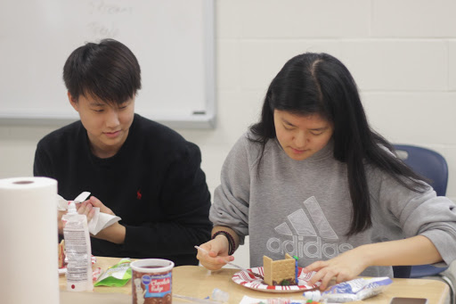 Senior Jongwan Kim watches senior Mina Kim construct the frame of her gingerbread house at Amnesty International’s annual Gingerbread Jail House.