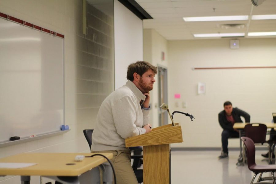 Guest speaker Kyle McDaniel  lectures on Trump's policies.