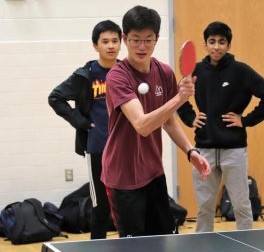 Ready for action, freshman Andrew Kim attempts to knock back the ball coming at him. Freshman Shreyas Chennamaraja and Alex Peal watch in the background as they wait for their match to begin. Photo courtesy of Forrest Meng.