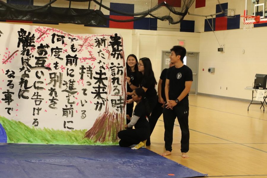 Senior Richard Wang explains the meaning behind their painting while his fellow peers hold up the artwork. The painting is performed every year and this year they decided to convey the message of growing up and maturing and essentially saying goodbye. This is due to the fact that many of the performers were seniors and used this as their farewell message.
