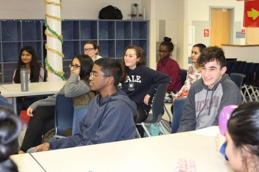 Attendees of the Kindness Pizza Extravaganzas Reveal Party listen to others introduce themselves