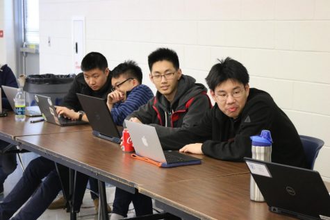 Seniors Kevin Wang, Benjamin Xu, James Kuang, and junior William Wang keep an eye on the team standings as participants scramble to fill out their answers.