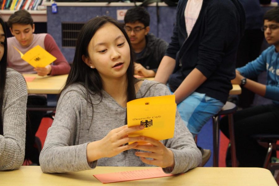 Reading across her menu, a student prepares to order traditional German food. 