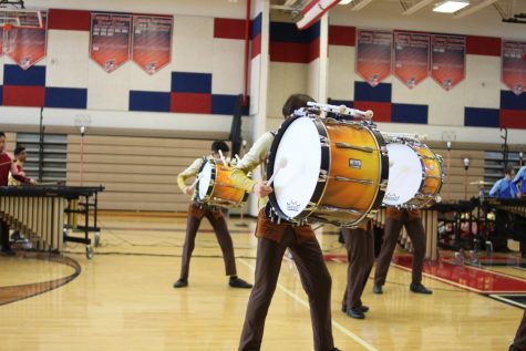 Leaning into his drum, freshman Benjamin Chang plays the instrument, complementing the other percussionists in the performance. “At the start of the season, I hadn’t even carried a bass drum before so it was hard to get started with drumline. But, as they say, practice makes perfect,” Chang said. “I just kept trying to stay upright with the drum throughout each rehearsal and eventually carrying it became easy.”
