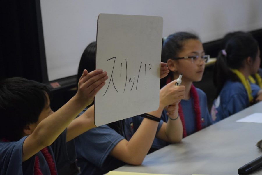 A student competing in the K-4 division’s championship round holds up their answer for a toss-up question.