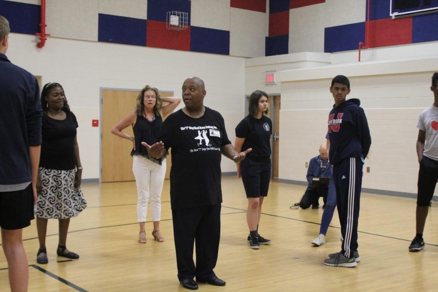 After Señora Gendive asks a question about a particular step, Instructor Morton gathers the attention of the other dancers and they all watch him repeat the step slowly.